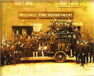 Old photo of Firefighters standing on and to the sides of firetruck - year not specified
